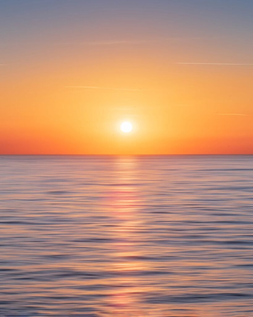 calm water with sun and orange sky
