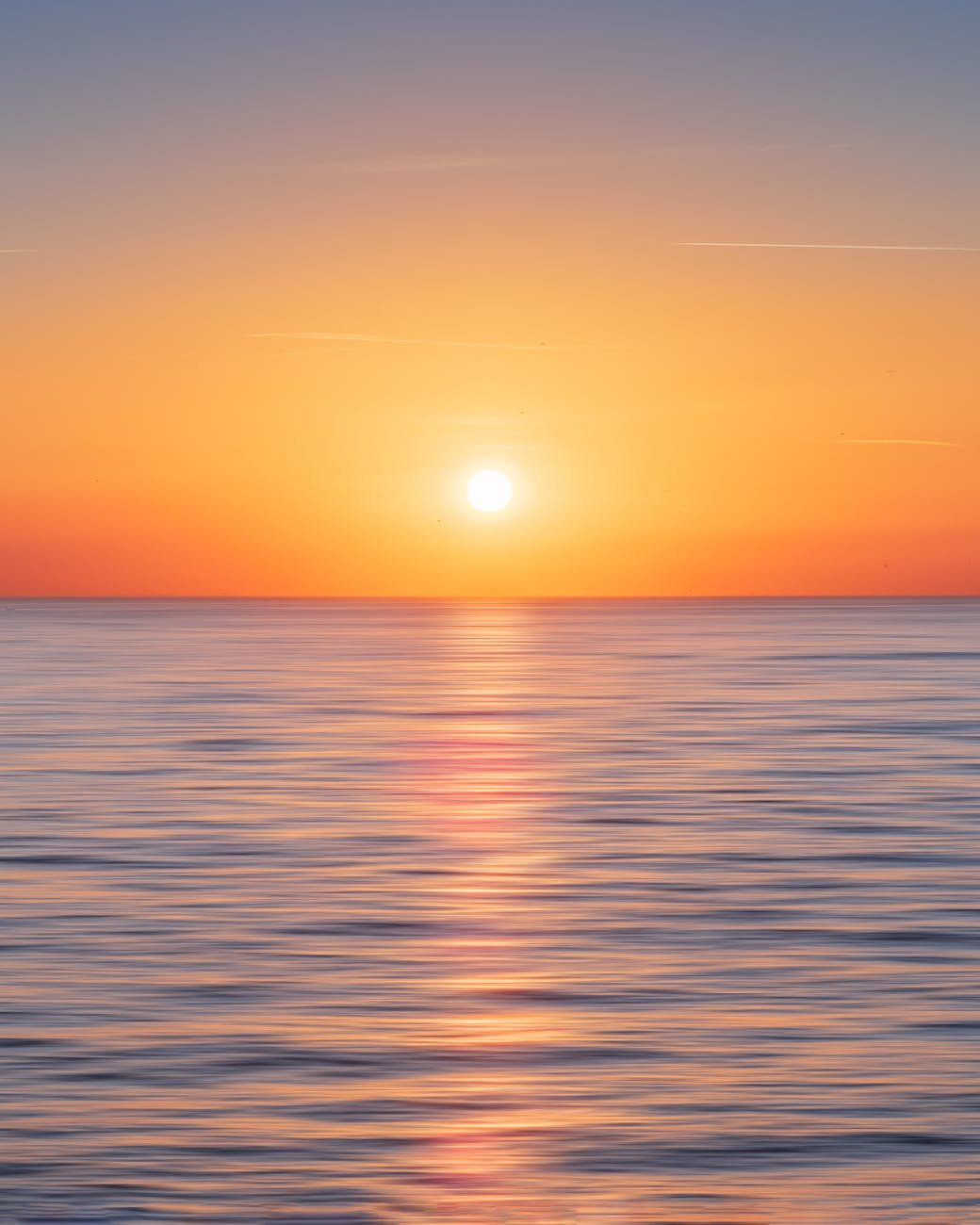 calm water with sun and orange sky
